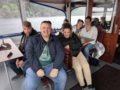 Die Gruppe sitzt gut gelaunt in der Kabine eines Ausflugsboots, draußen ist der Stausee zu sehen.