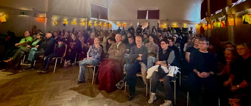 Ein voll besetzter Saal mit Zuschauerinnen und Zuschauern im warmen Licht von Papierlaternen.