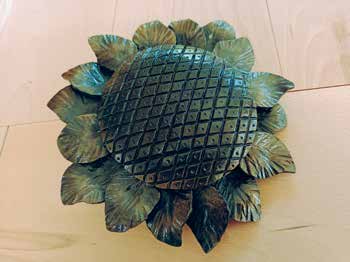 Eine geschmiedete Sonnenblume aus dunklem Metall mit gewellten Blütenblättern und gitterartigem Blütenkorb.