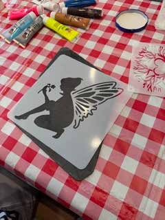 Eine Schablone mit einer Fee liegt auf einer Schiefertafel.